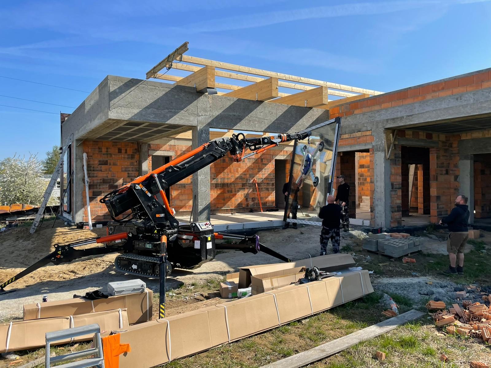 Wysięgnik mini żurawia BG Lift M250 wprowadza przeszklenie pod betonowy strop parterowego domu w Trzebnicy