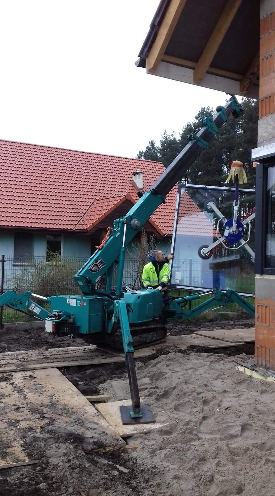 Mini żuraw gąsienicowy z ssawką próżniową przy montażu okna w domu jednorodzinnym w Chrząstawie koło Wrocławia
