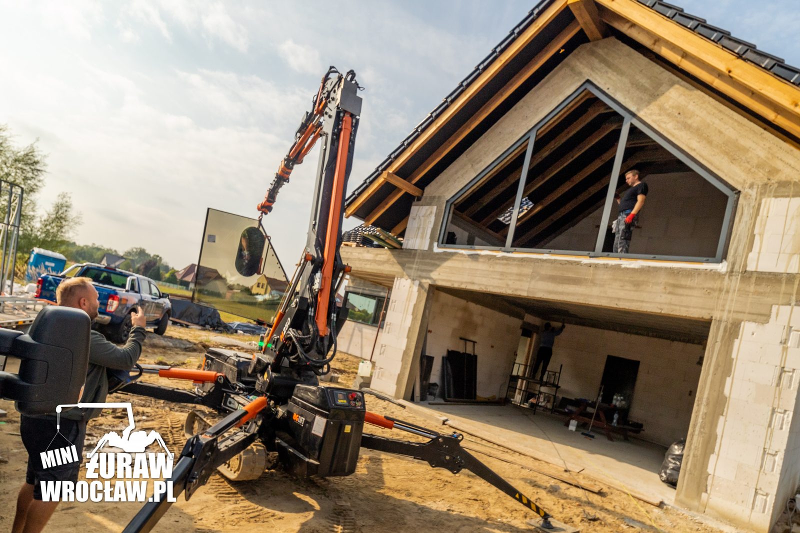 Mini żuraw BG Lift M250 z ssawką próżniową podnosi dużą szybę do przeszklenia szczytu domu w Kiełczowie pod Wrocławiem