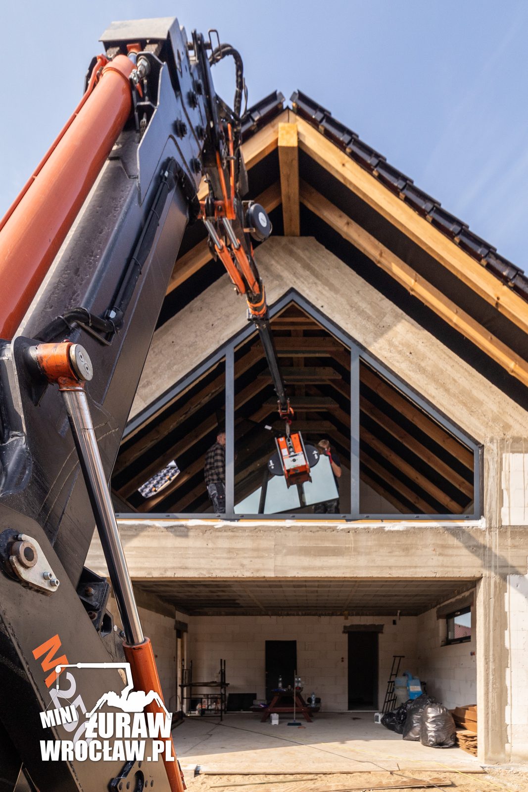 Wysięgnik mini żurawia BG Lift M250 z ssawką próżniową przy trapezowym przeszkleniu szczytowym domu w Kiełczowie